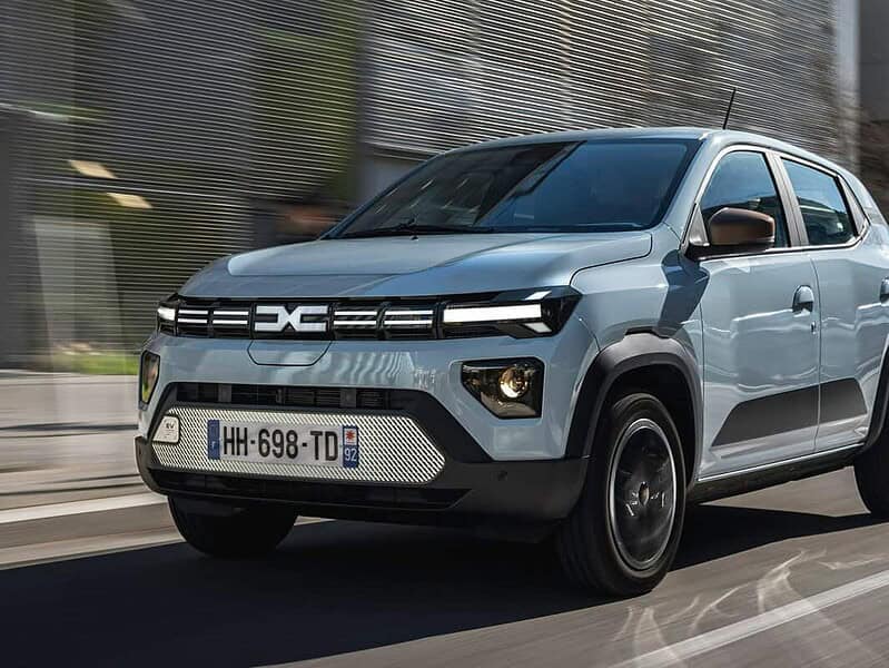 Noua generație Dacia Spring, în versiune gri-argintiu, în mers pe o stradă urbană